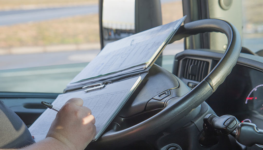 Closeup Of A Truck Driver Writing On A Clipboard Inside Of A Truck Cabin Renting Vs Buying A Trailer