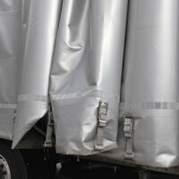 Closeup Of A Grey Tarp Hanging Over The Side Of A Trailer Tarp System Maintenance